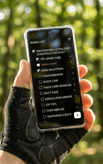 A user checking their ultralight gear list in the woods. This image demonstrates the app's True Black dark mode and offline capability, perfect for outdoor adventures where signal is weak.